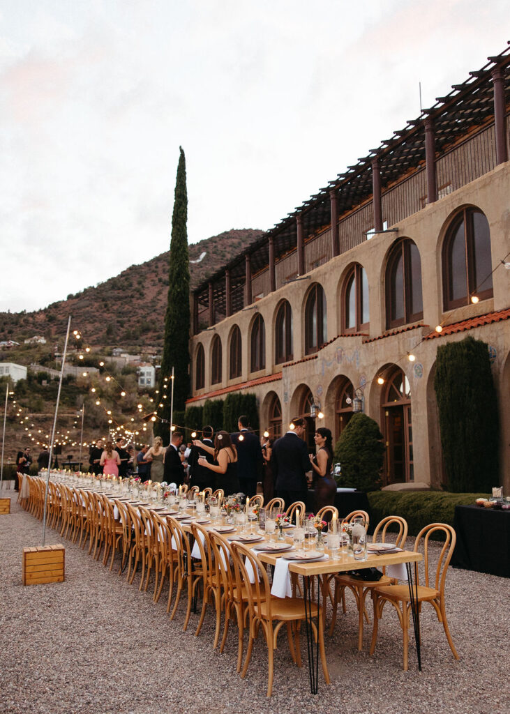 Long reception table under string lights beside the historic Little Daisy estate in Jerome at dusk