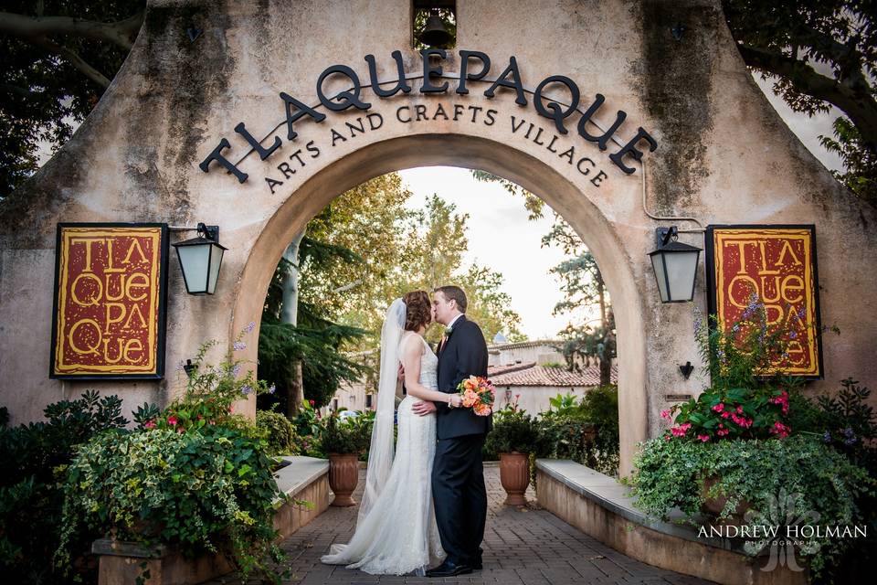 Newlyweds sharing a kiss beneath the Tlaquepaque Arts and Crafts Village arch in Sedona